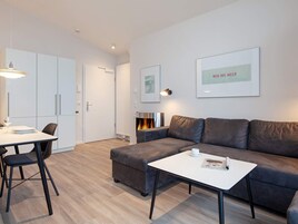 Una sala de estar moderna con un sofá, una mesa de centro, una mesa de comedor con sillas y una chimenea.