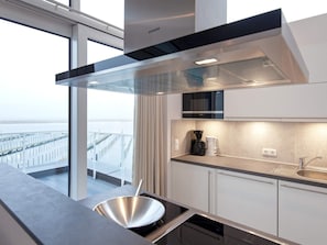 Cozinha moderna com exaustor de aço inoxidável, micro-ondas embutido e uma grande janela com vista para uma ponte.