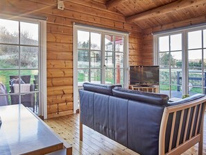 A wooden interior with a sofa, a television, and a table.