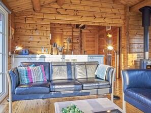 Interior acogedor de una cabaña con un sofá de cuero, una mesa de centro y un estufa de leña.