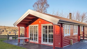 A red wooden cabin with a covered porch and large windows. - 4 Person Holiday Home in Allinge (Allinge)
