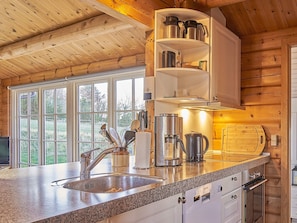 Cozinha com bancada de granito, eletrodomésticos de aço inoxidável e janela com vista para uma paisagem verde.