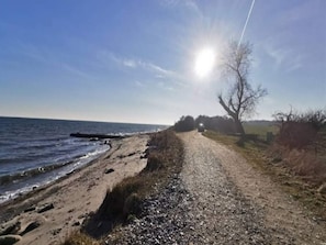 Een grindpad naast een strand, met de oceaan en een heldere lucht.