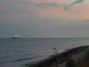 A ship on the water with a rocky shoreline in the foreground. - 6 Person Holiday Home in Rudkobing (Rudkobing)