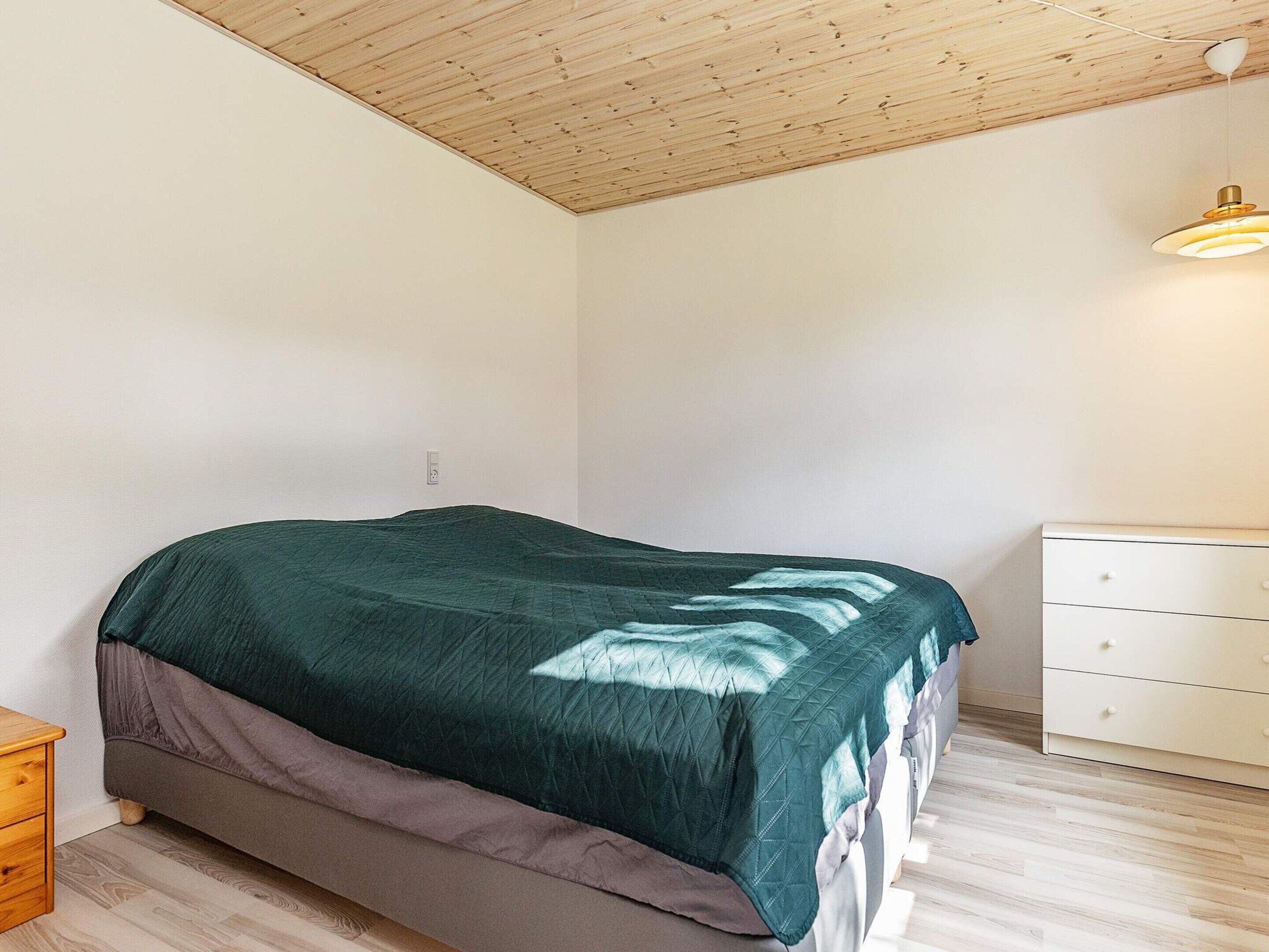A bedroom with a bed, a dresser, and a ceiling light.