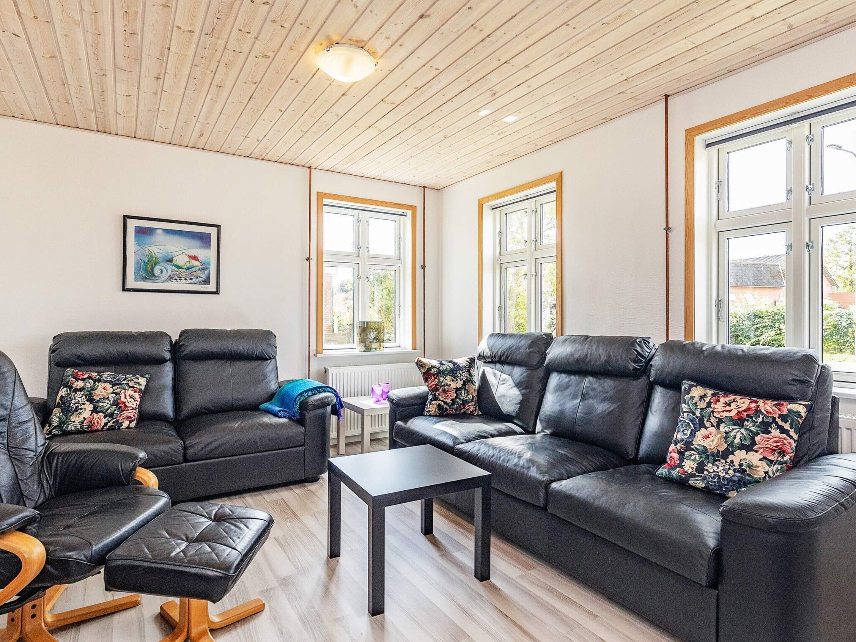 A living room with two black leather sofas, a wooden coffee table, and a framed picture on the wall.