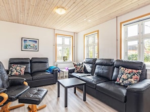 Een woonkamer met twee zwarte leren banken, een houten salontafel en een lijst met een foto aan de muur.