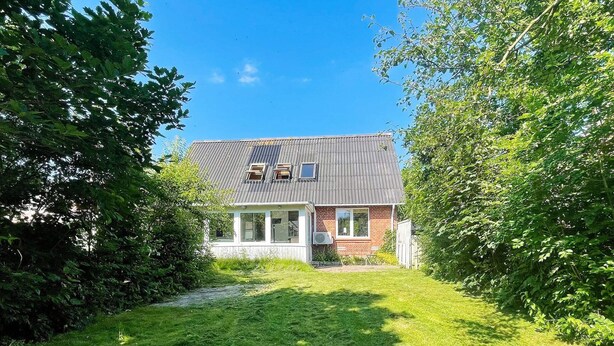 Et toetagers hus med skråtag, en veranda og en lille forhave.