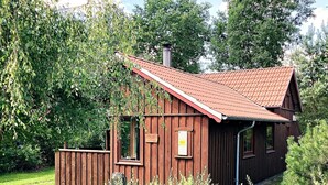 Punatiilikattoinen puumökki, jonka ympärillä on vehreää kasvillisuutta.