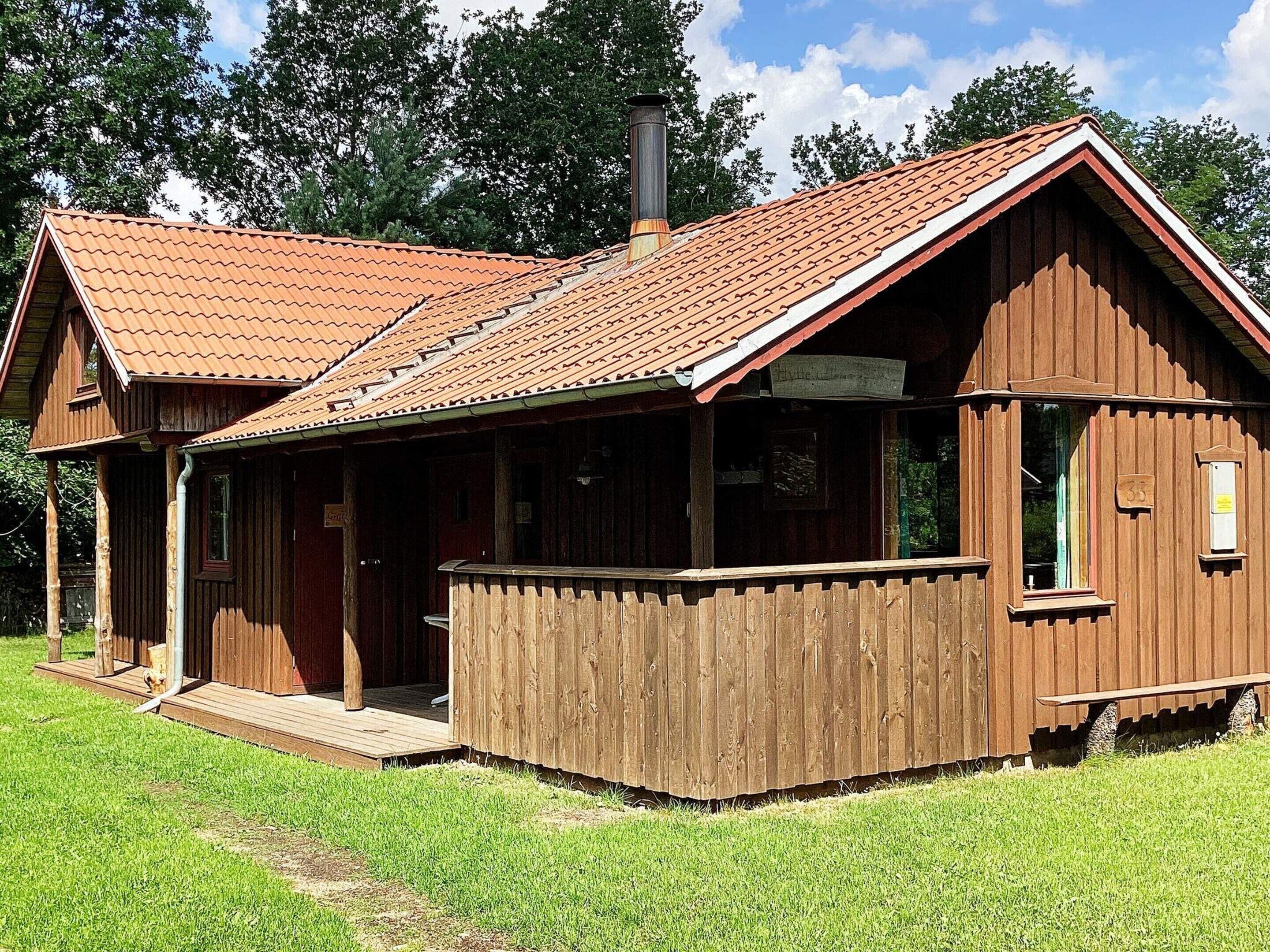 Una baita di legno con tetto spiovente, un portico e un camino.