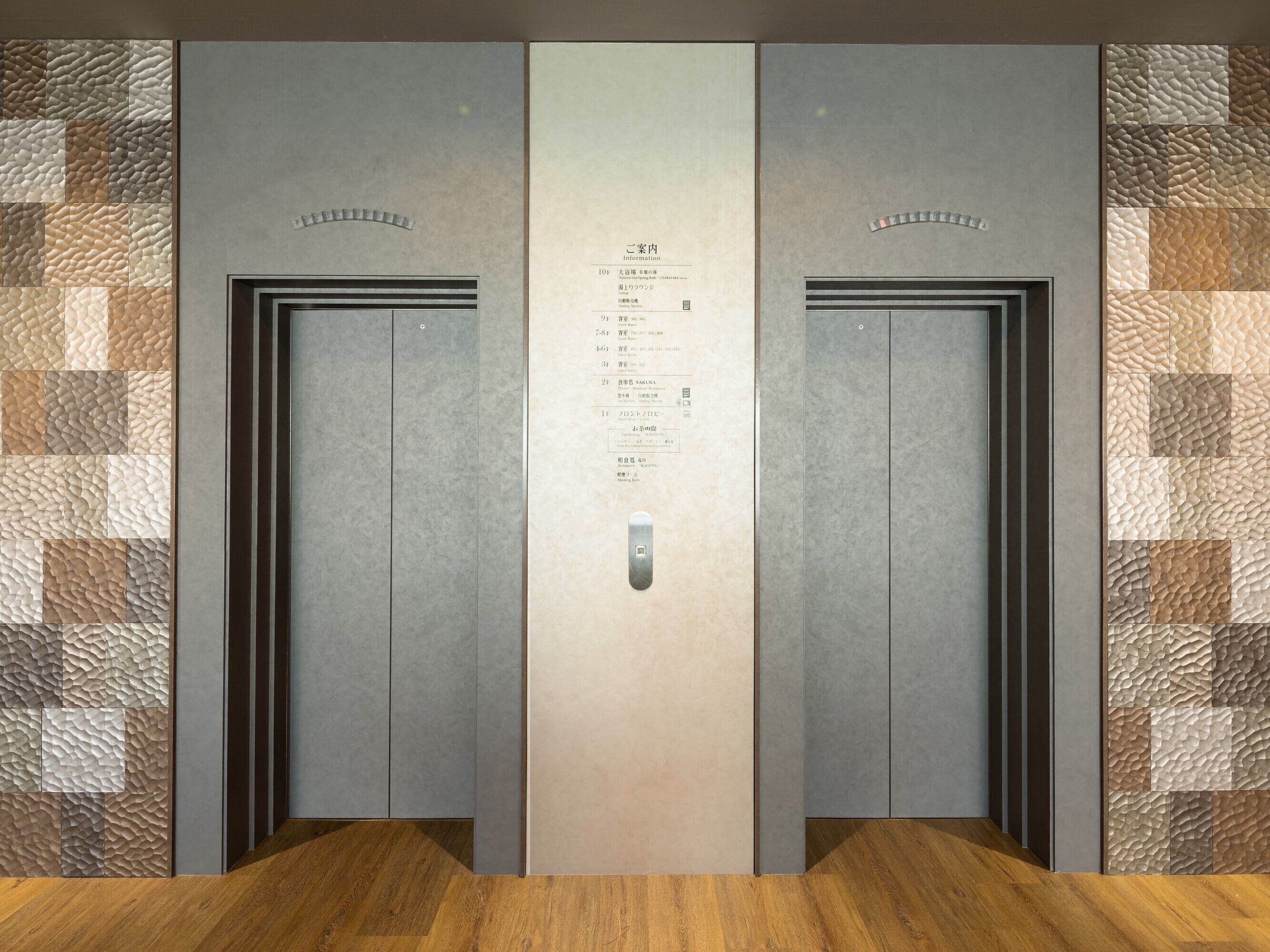 Un ascensor moderno con un panel de pared texturizado y un tablero de control con información.