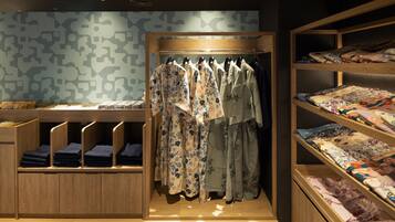 Una habitación ordenada con un perchero, estantes con textiles doblados y una pared estampada.