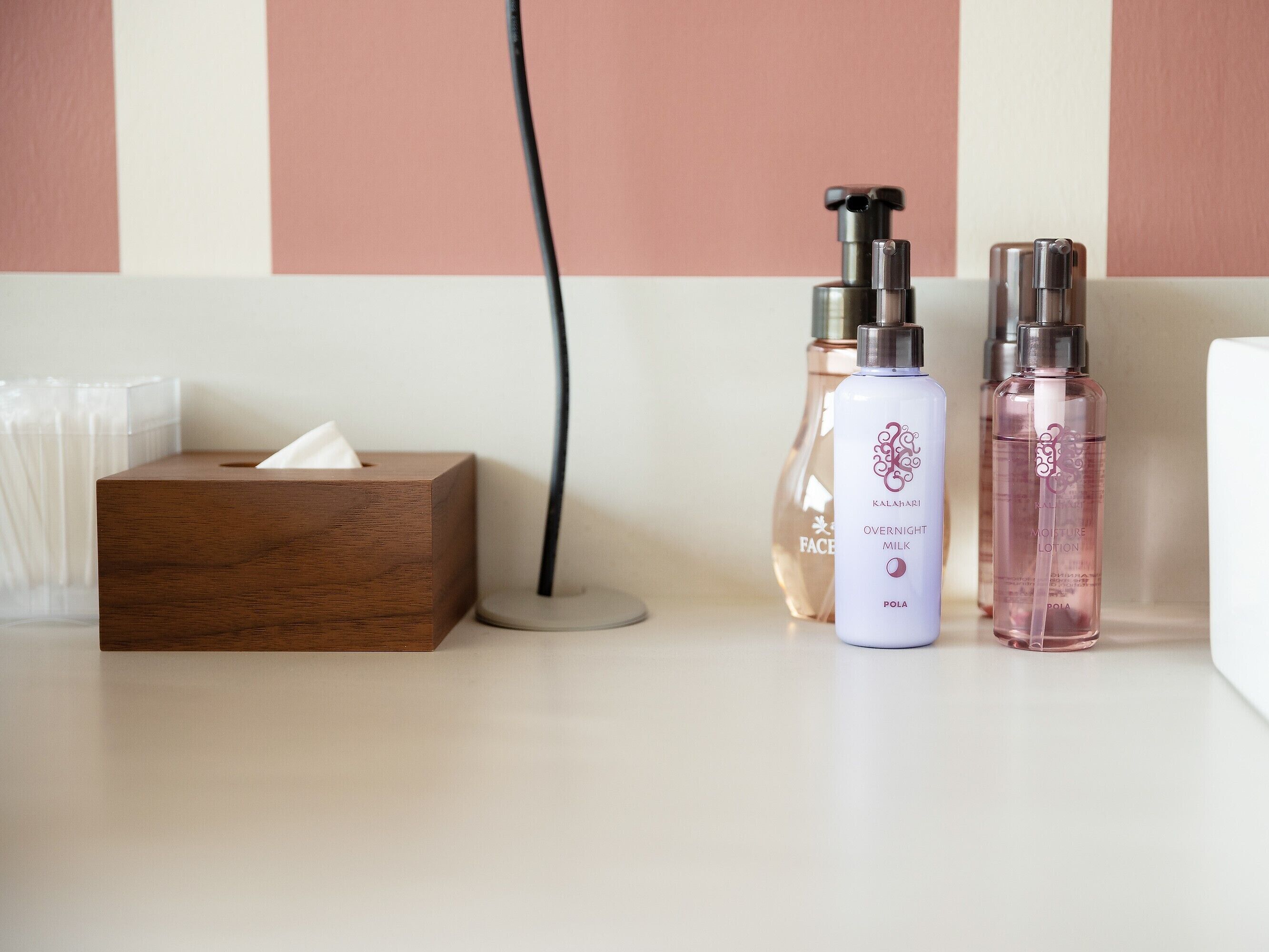 A bathroom counter with a tissue box, a hairdryer, and two bottles of lotion.