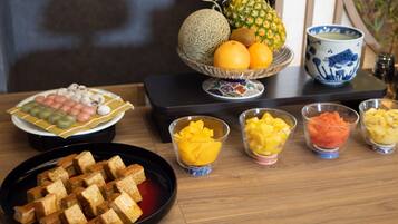 A table with various food items including bread, fruits, and a bowl of sweets.