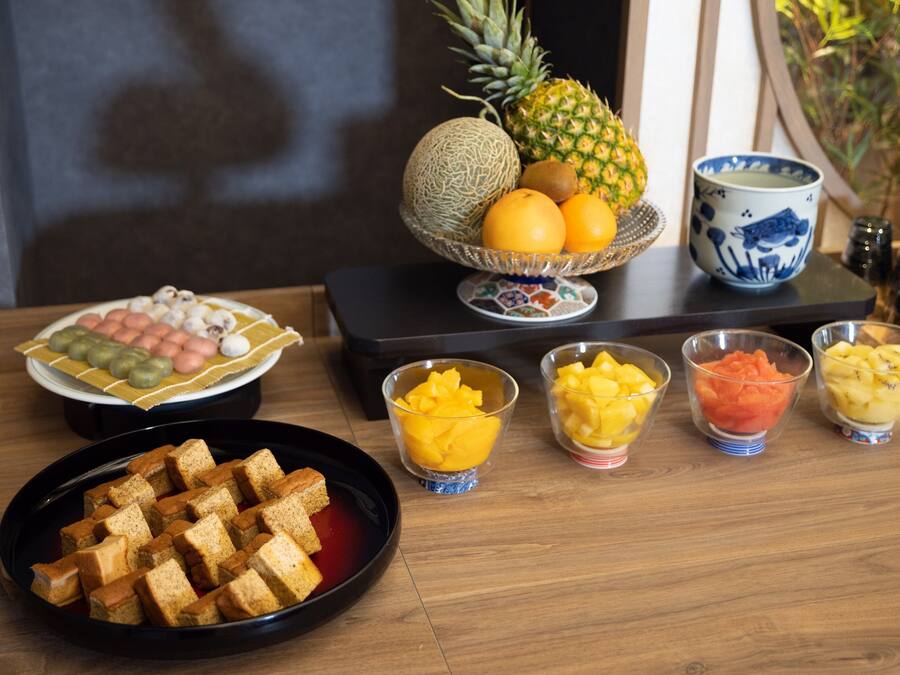 A table with various food items including bread, fruits, and a bowl of sweets.