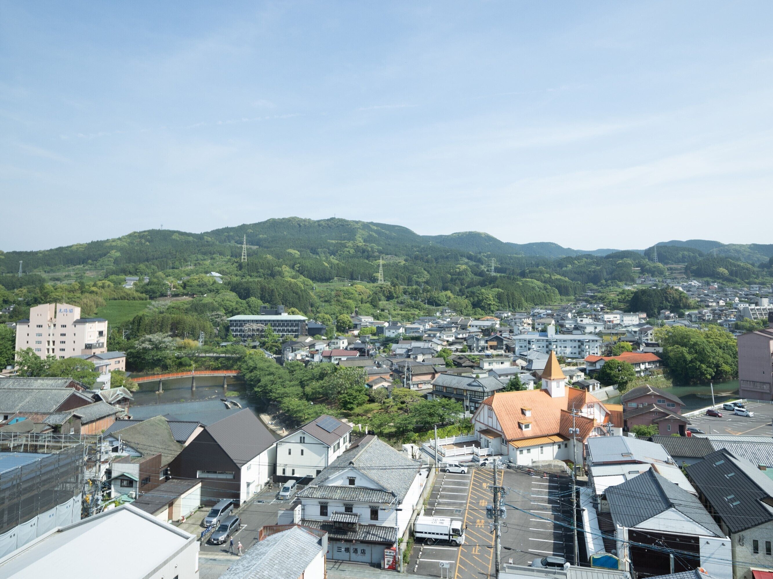 A town with a mix of traditional and modern buildings, surrounded by green hills.