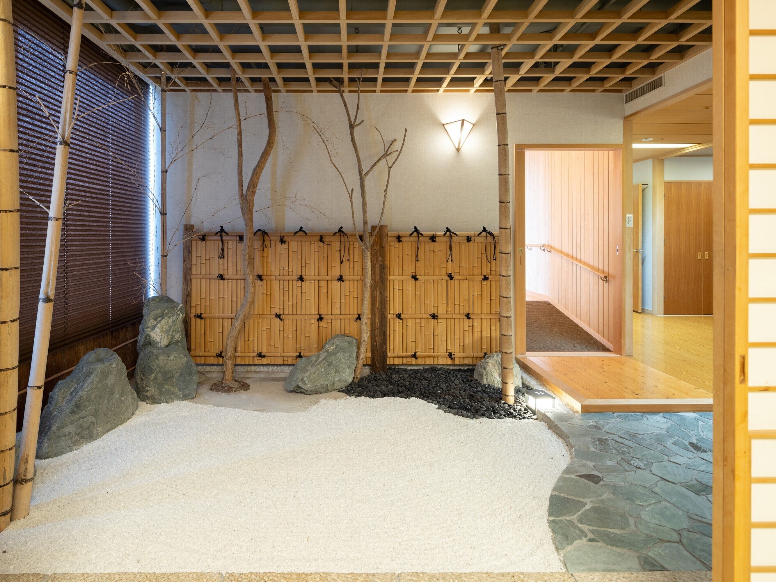 Un interior japonés tradicional con suelo de tatami, un separador shoji y una pared de madera con cuerdas negras colgando.
