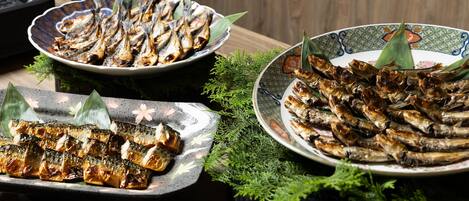 Una mesa con tres platos de pescado a la parrilla, adornados con hojas.