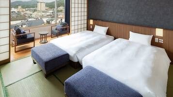 A hotel room with two beds, a view of the city, and traditional Japanese decor.