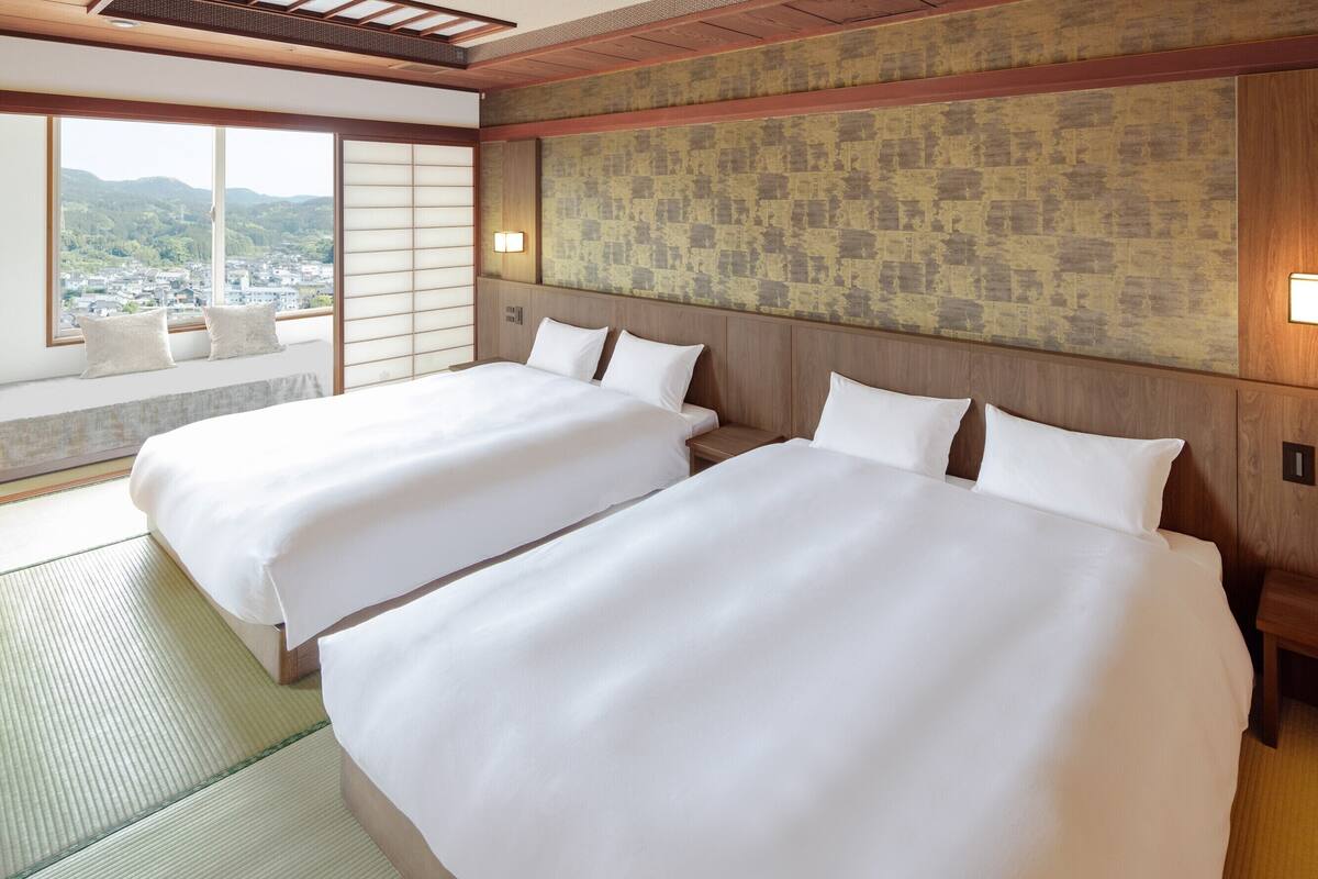 A hotel room with two beds, a view of the city, and a tatami mat floor.