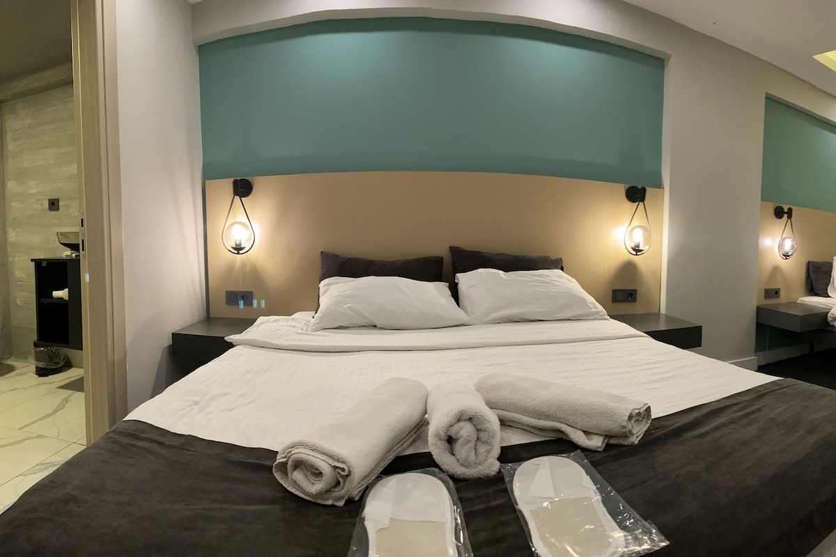 A hotel room with two beds, a bathroom, and a hallway.