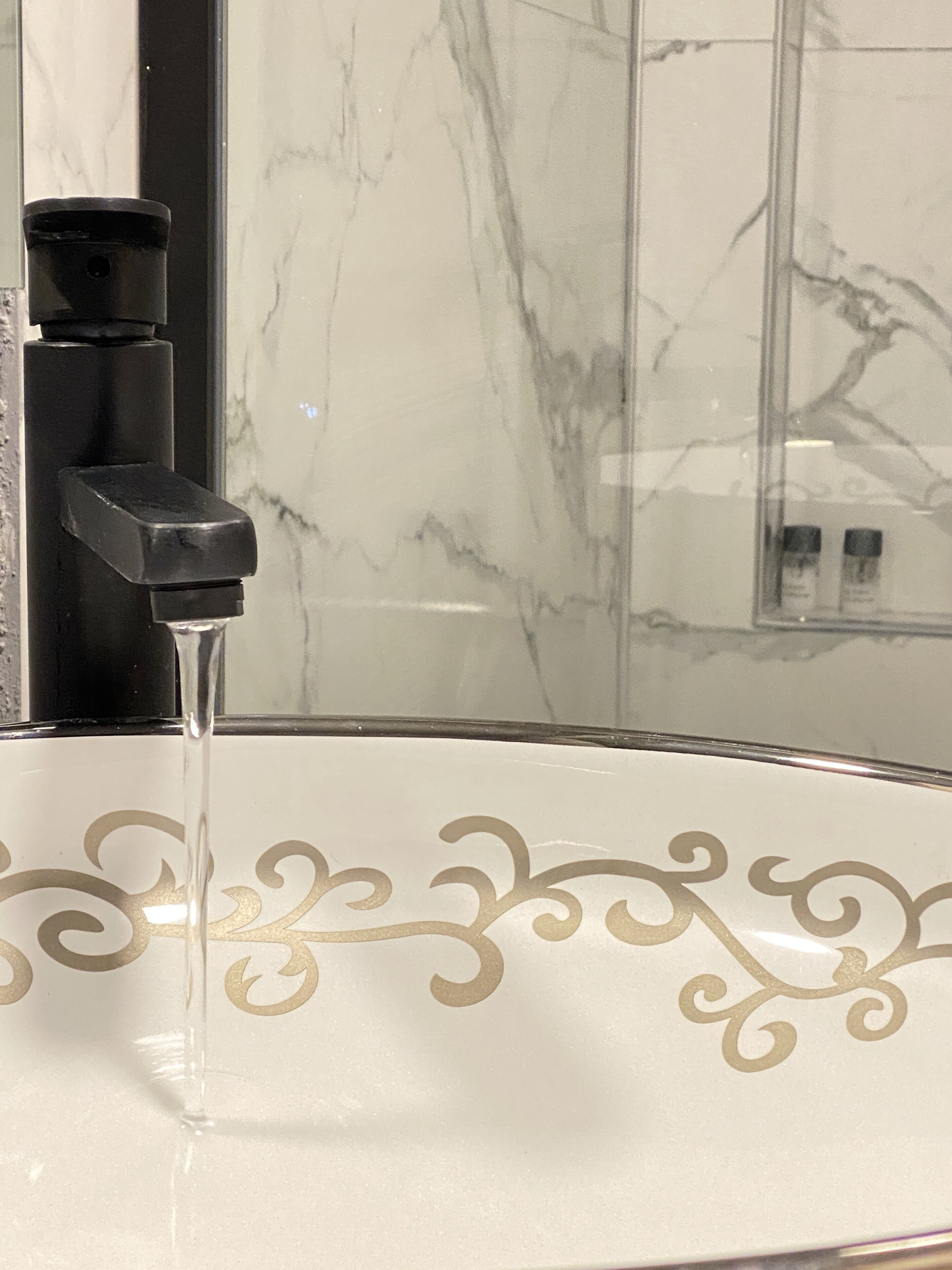 A bathroom sink with a marble backsplash and a faucet.