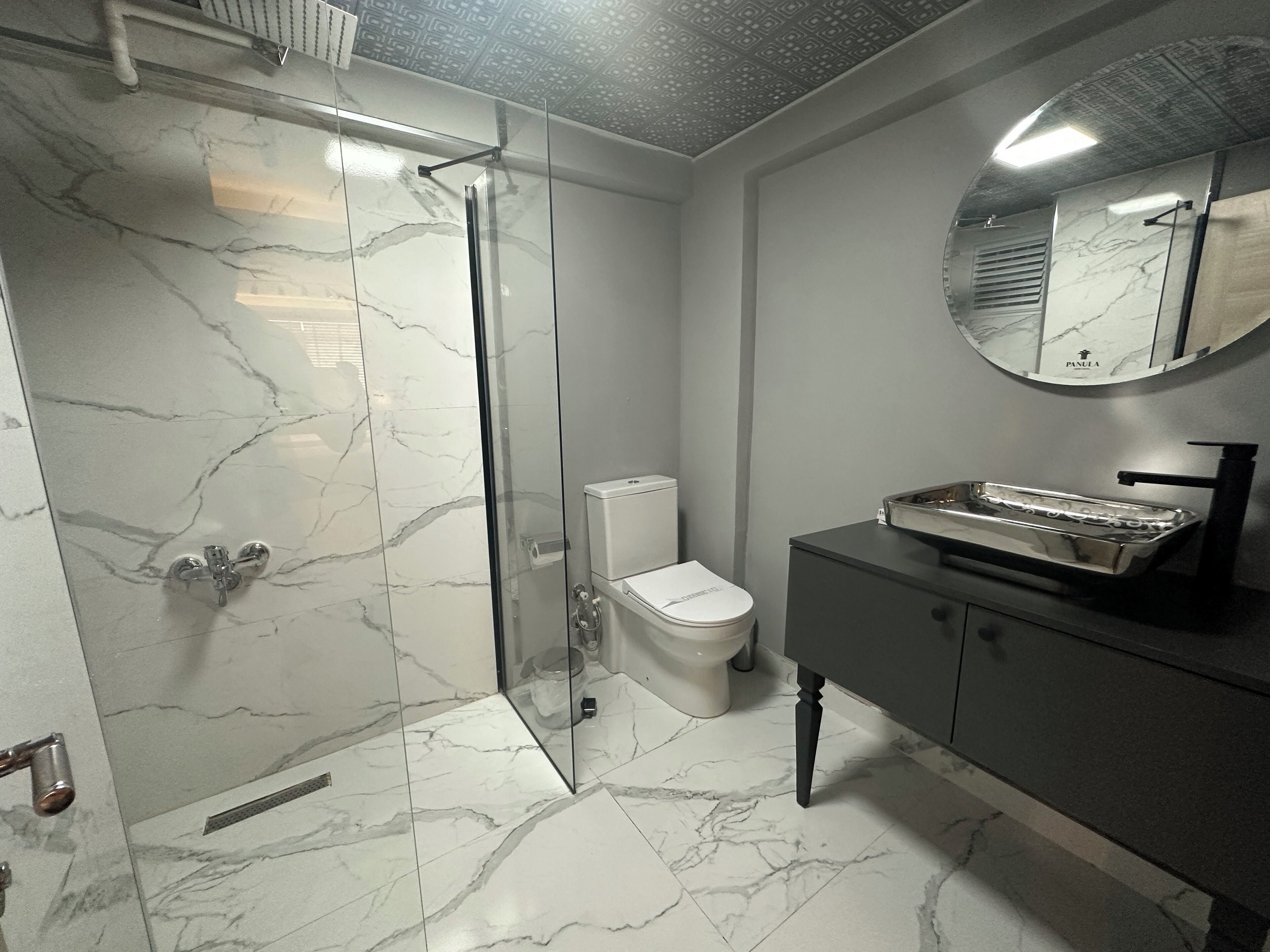 A modern bathroom with a glass-enclosed shower, a toilet, and a vanity with a sink and mirror.
