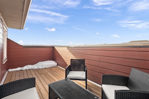 Relax in a serene outdoor space with a wooden deck, two comfortable chairs, and a small table.