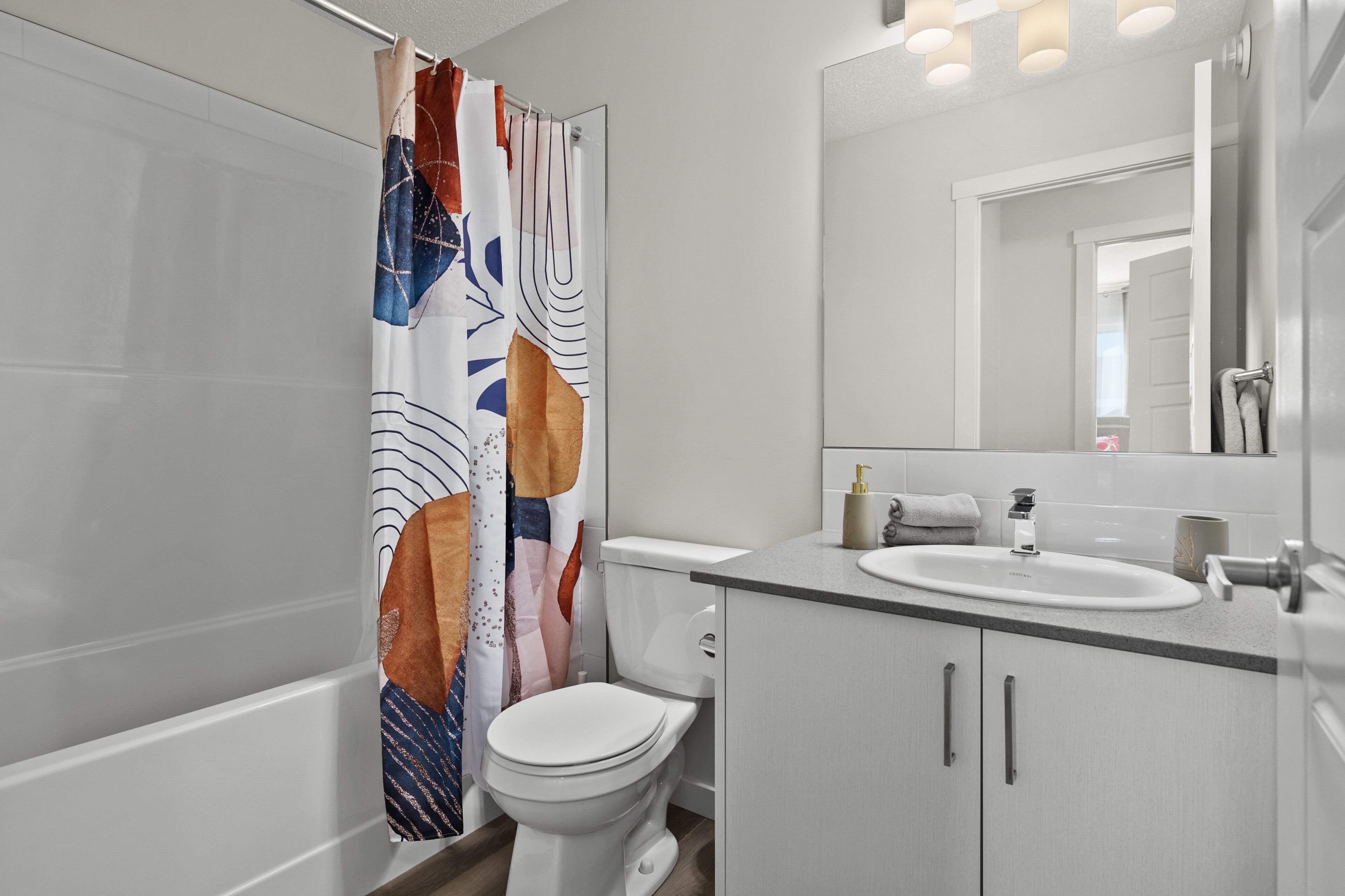 A modern bathroom with a toilet, sink, and mirror.