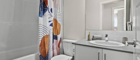 A modern bathroom with a toilet, sink, and mirror.