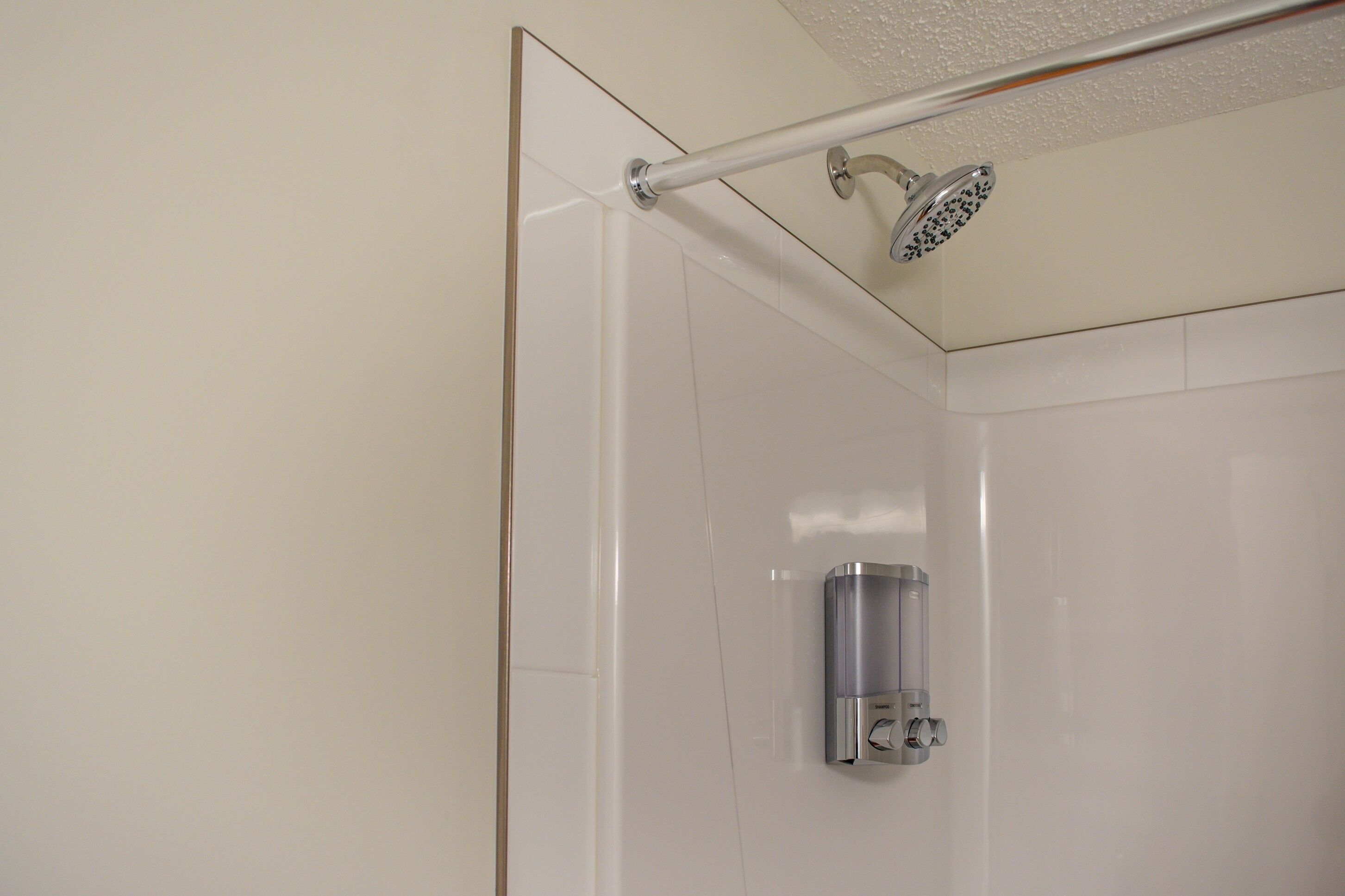 Una ducha con cabezal de ducha de mano y panel de control en la pared.