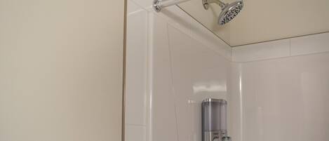 Una ducha con cabezal de ducha de mano y panel de control en la pared.