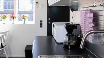 Una cocina con cafetera, tostadora y pileta. Hay plantas en macetas en el alféizar de la ventana.