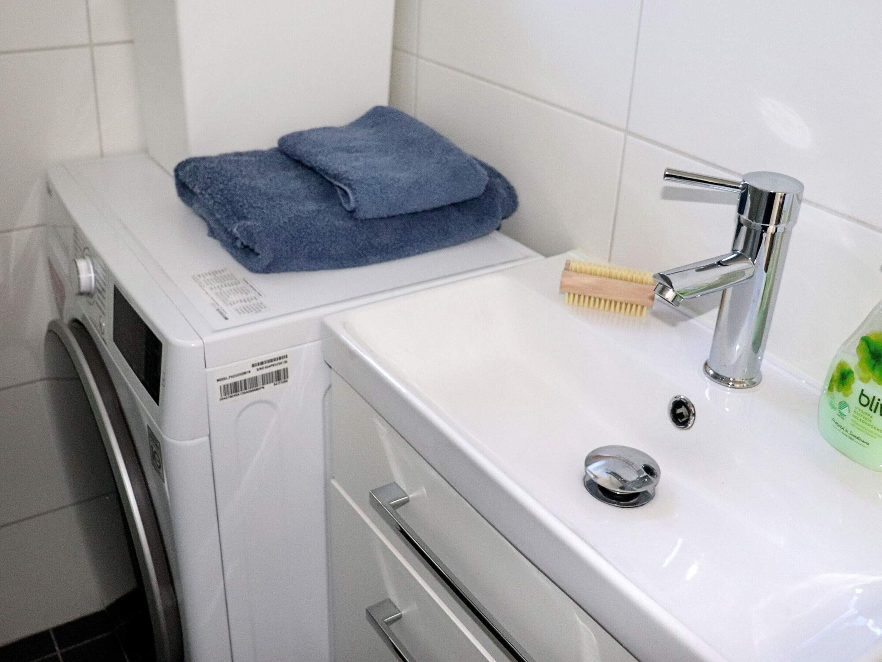 A compact laundry area with a washing machine, a sink, and a blue towel on the machine.