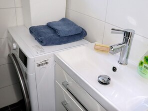 A compact laundry area with a washing machine, a sink, and a blue towel on the machine. - 4 Star Holiday Home in Varberg (Varberg)