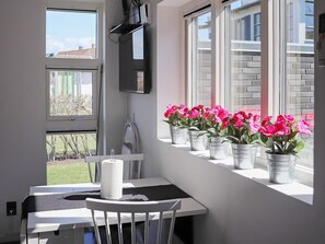 A room with a window sill lined with potted plants, a white chair, and a table with a roll of toilet paper. - 4 Star Holiday Home in Varberg (Varberg)