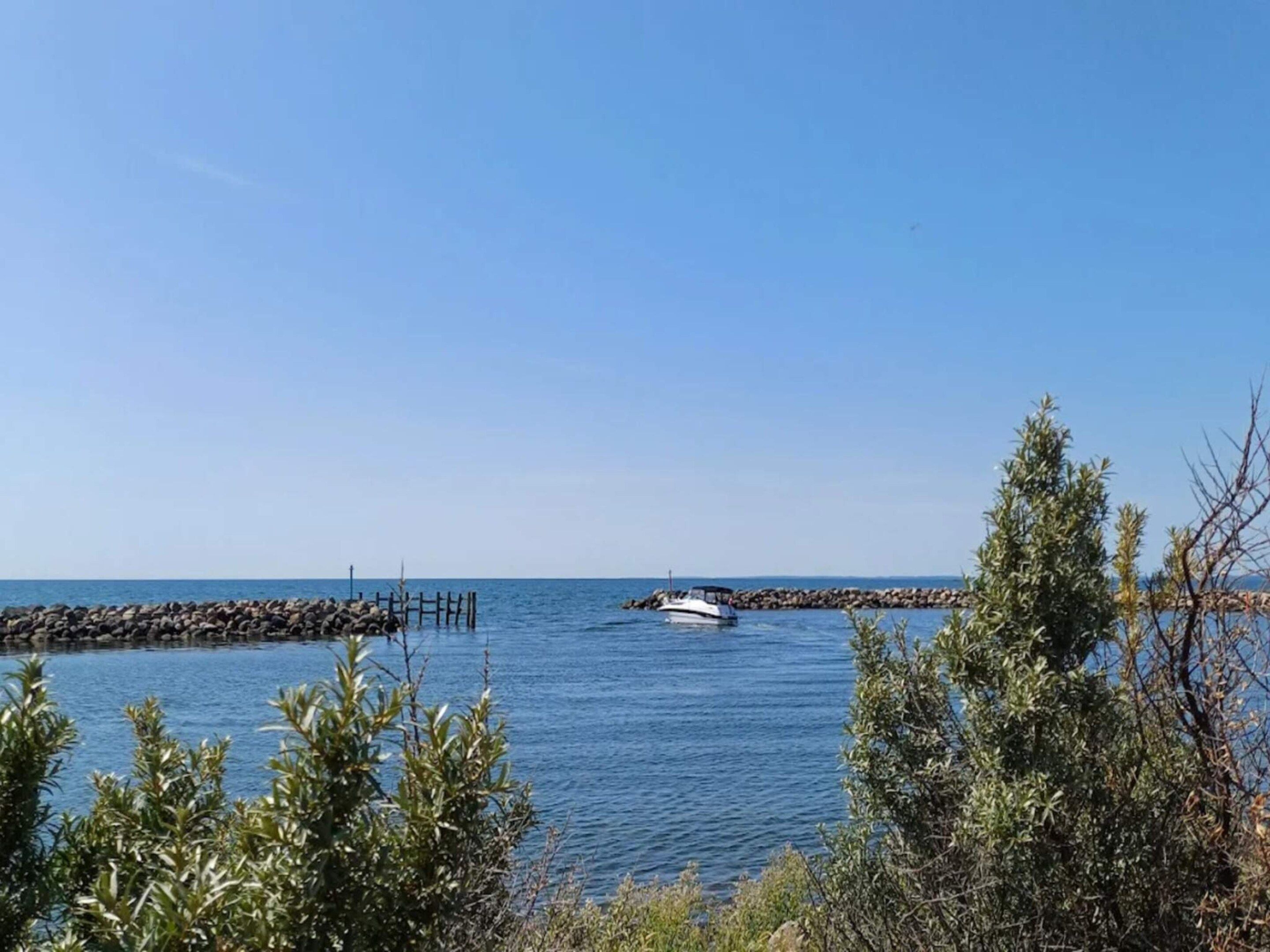 A calm body of water with a boat, surrounded by rocky shores and dense greenery.