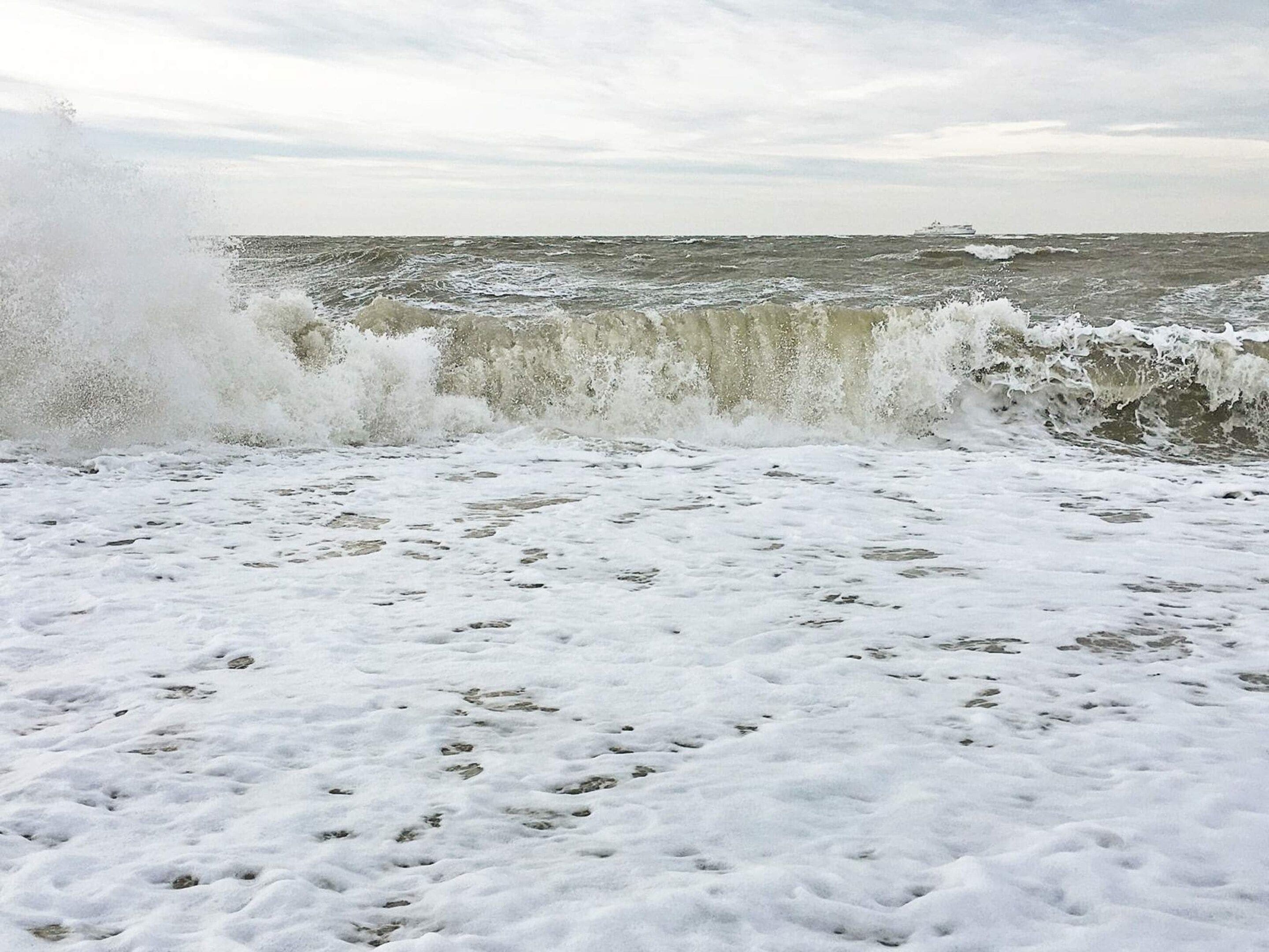 A beach with waves crashing onto the shore, creating a foamy texture on the sand.