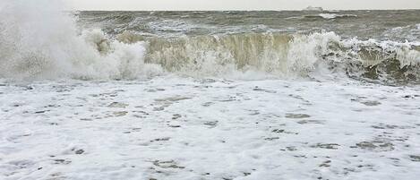 A beach with waves crashing onto the shore, creating a foamy texture on the sand.