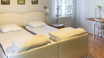A hotel room with a bed, a bedside table, a lamp, a chair, and a window with floral curtains.