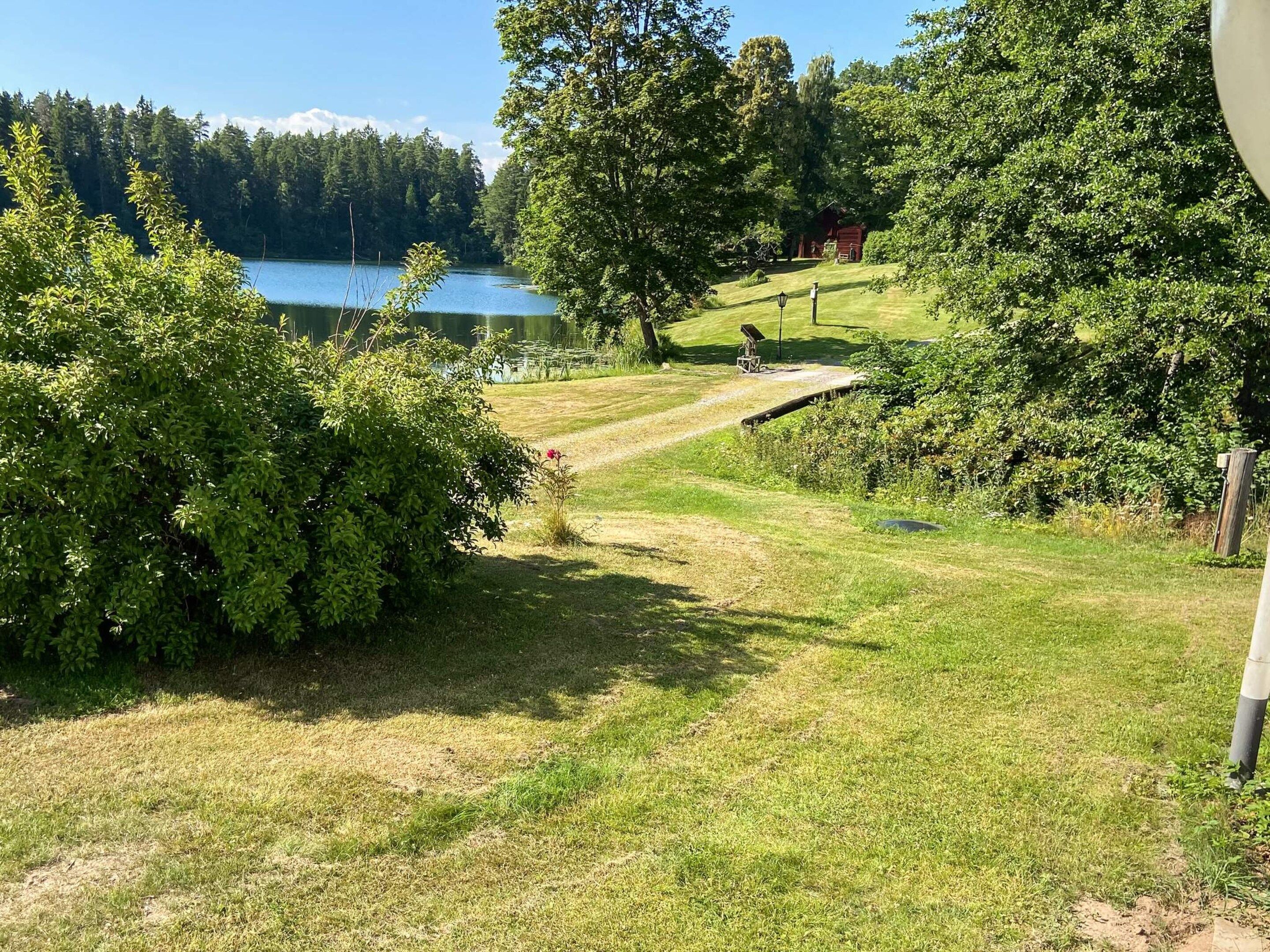 Zona verde con una terraza de madera y un lago al fondo.