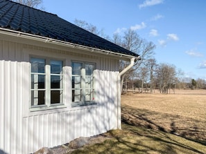 A white building with a dark roof, a window with a white frame, and a white fence. - 5 Star Holiday Home in Asbro (Asbro)