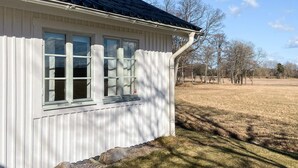Valkoinen rakennus, jossa on tumma katto, valkorunkoinen ikkuna ja valkoinen aita.