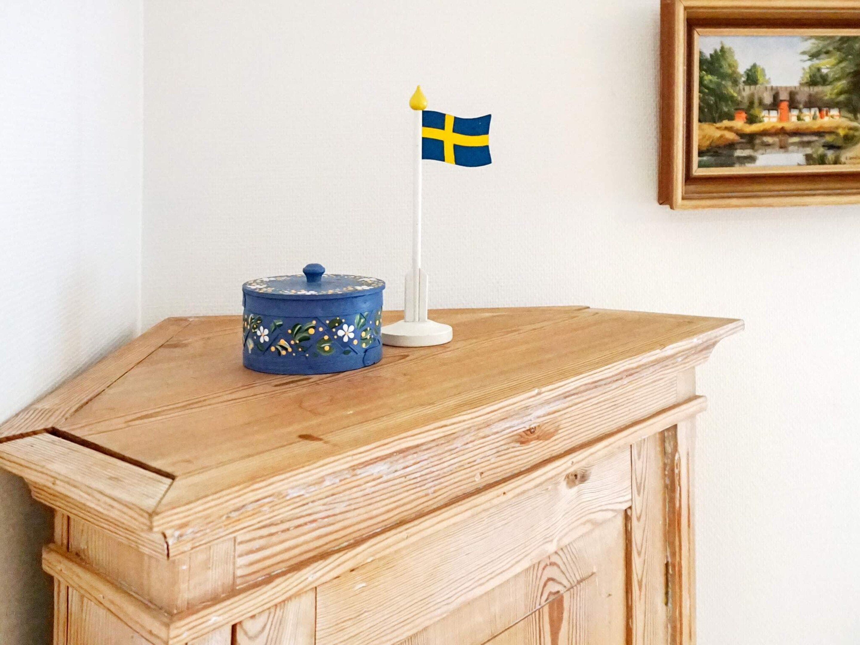 A wooden table with a blue container and a small Swedish flag.