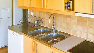 A kitchen with two stainless steel sinks, wooden cabinets, a dish rack, and a built-in oven.