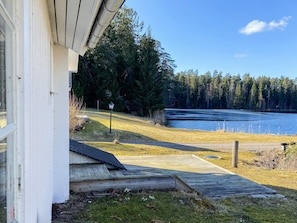 Una casa amb una terrassa de fusta que dona a un llac, envoltada d'arbres.