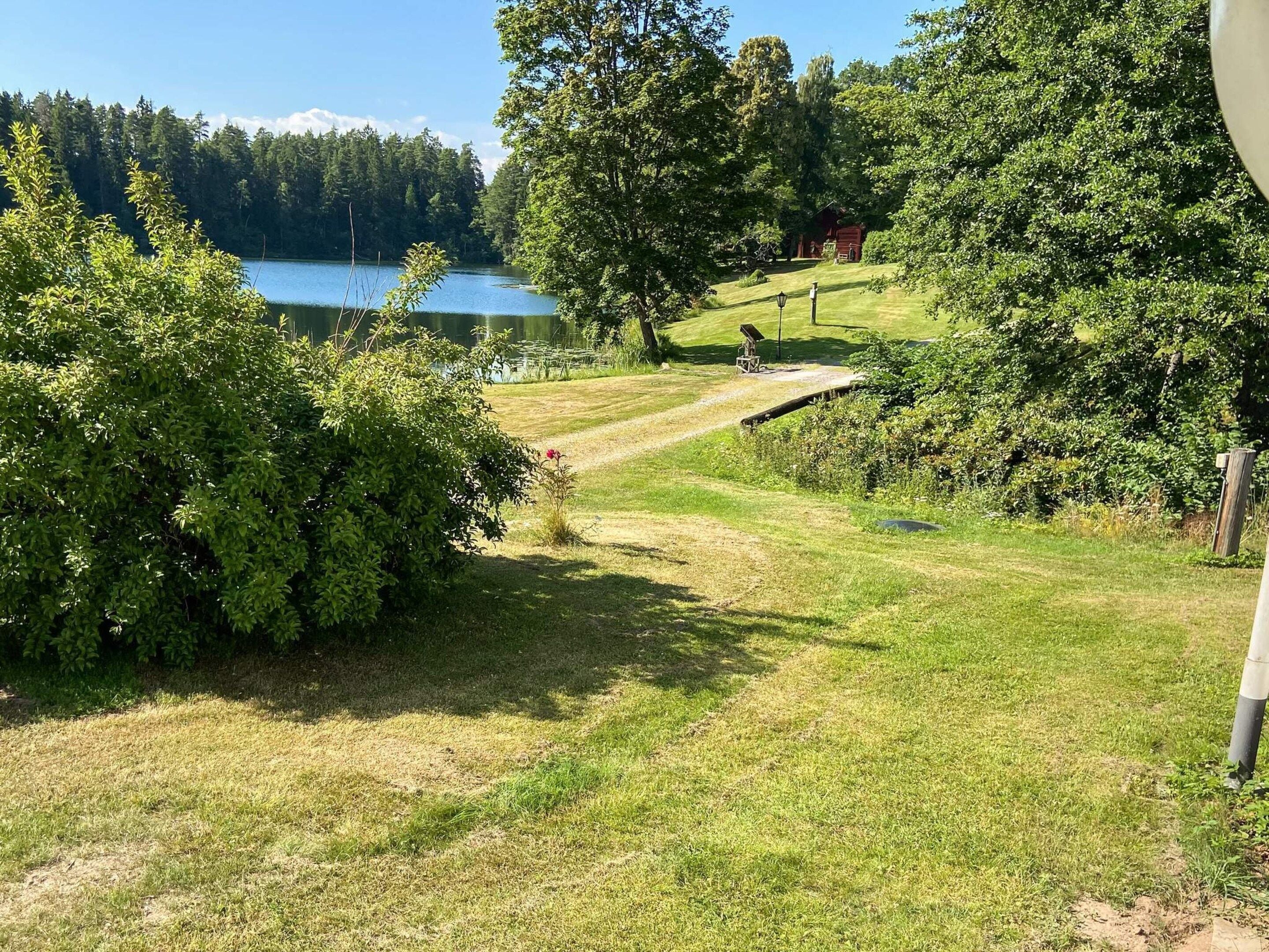 A grassy area with a wooden deck and a lake in the background.