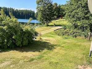 Un área verde con una terraza de madera y un lago al fondo.