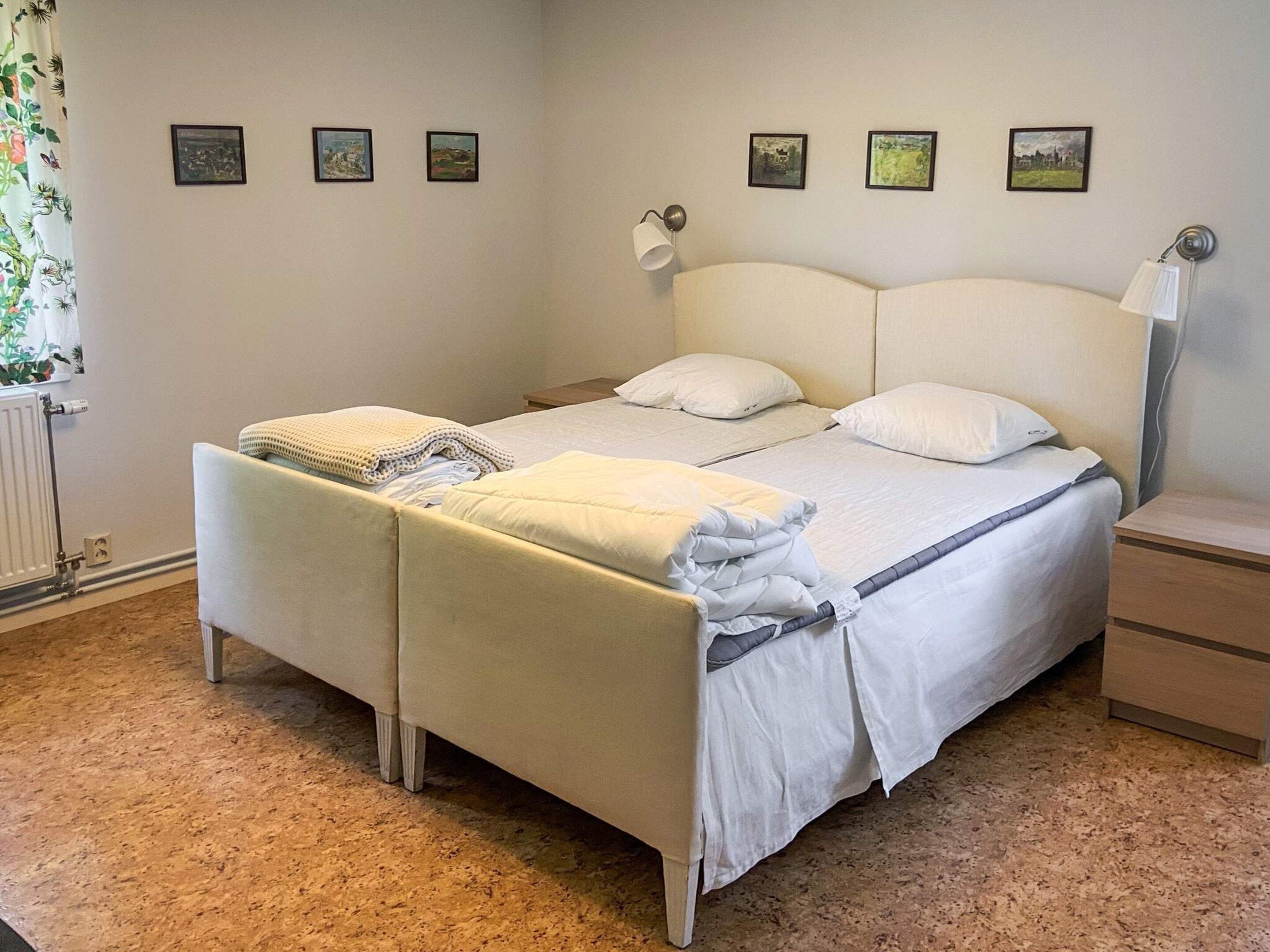 A double bed with a headboard, two bedside tables, and a window with curtains.