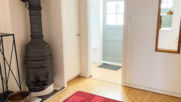 A room with a wood-burning stove, a red rug, and a door leading to another room.